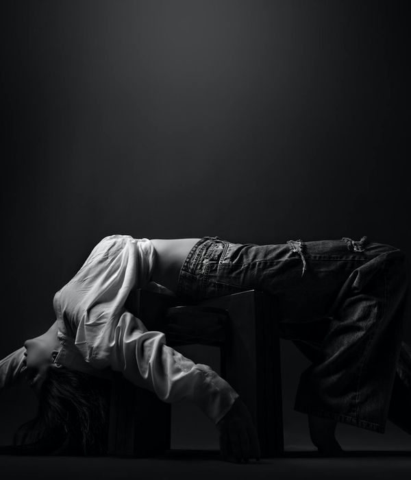 Woman in a dynamic, flowing movement pose in a minimalist studio.